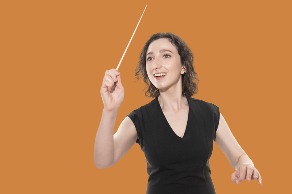 Female conducting student holding baton and smiling on orange background